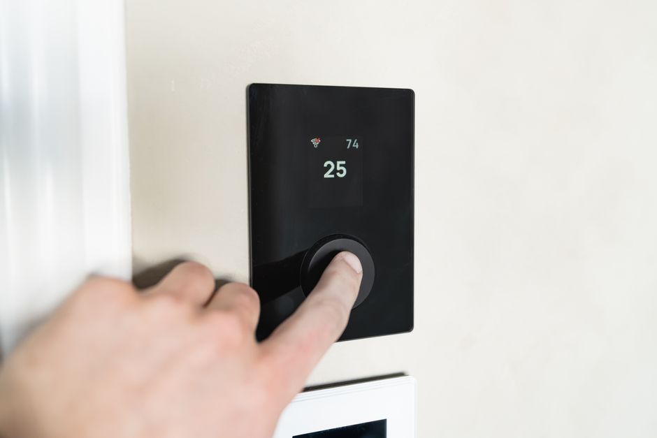 Homeowner adjusting a smart thermostat for AC control